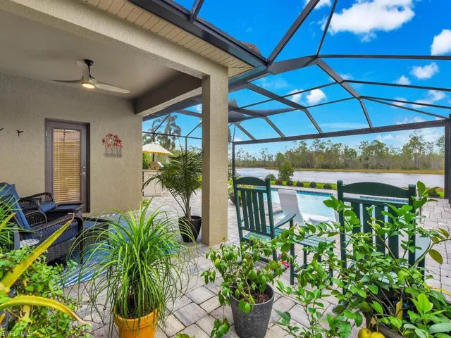View of patio featuring glass enclosure, ceiling fan, and a water view