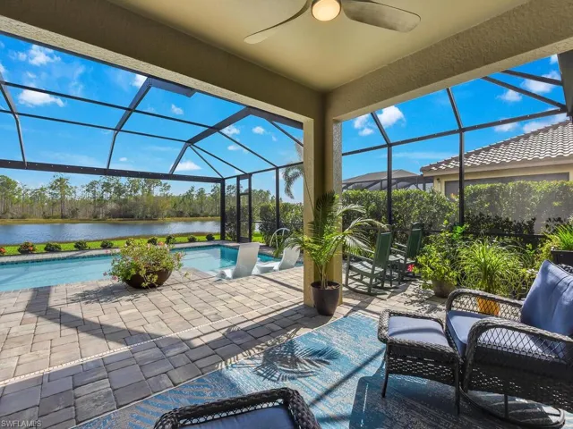 View of patio featuring a water view, ceiling fan, and a lanai
