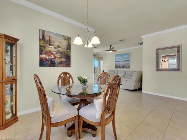Dining room featuring crown molding, light tile patterned floors, and ceiling fan with notable chandelier