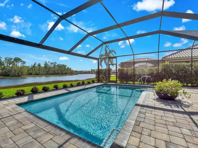 View of swimming pool featuring glass enclosure, a patio area, and a water view