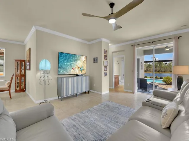 Tiled living room with ceiling fan and ornamental molding