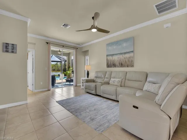 Living room with ceiling fan, light tile patterned flooring, and ornamental molding