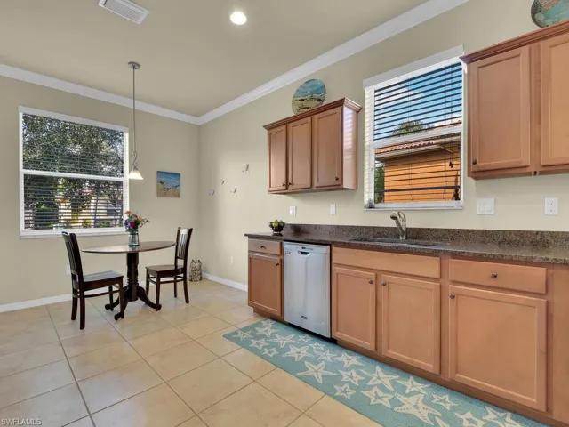 Kitchen with dishwasher, light tile patterned floors, ornamental molding, and sink