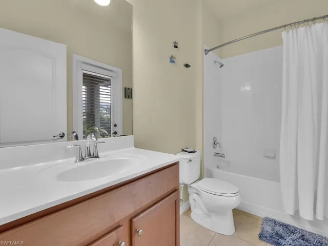 Full bathroom with toilet, vanity, tile patterned floors, and shower / tub combo with curtain