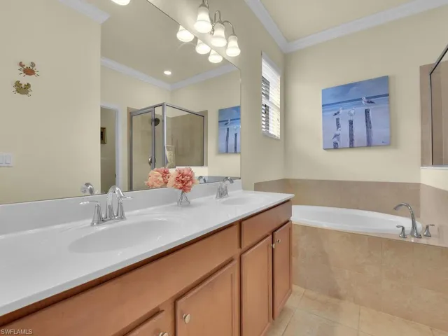 Bathroom featuring shower with separate bathtub, vanity, tile patterned floors, and crown molding