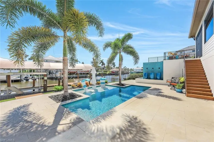 Outdoor pool with stairs, boat lift, a dock, a water view, and a patio