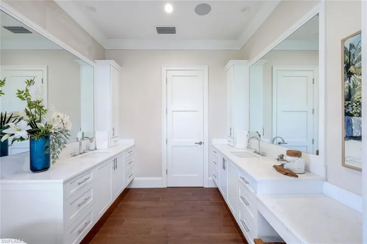 Bathroom featuring wood finished floors, two vanities, and crown molding