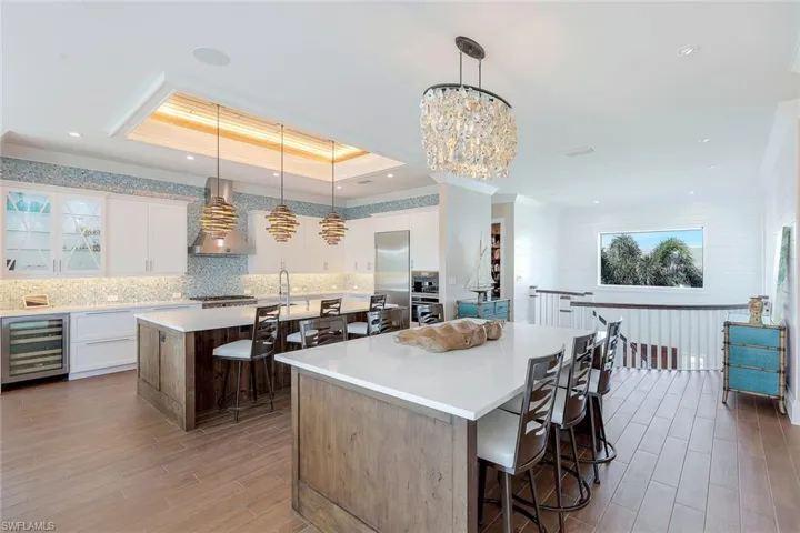 Kitchen featuring wall chimney range hood, wine cooler, a kitchen island, a kitchen breakfast bar, and ornamental molding