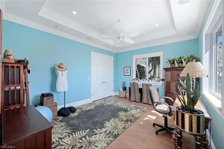 Home office with a tray ceiling, a ceiling fan, wood finished floors, recessed lighting, and baseboards