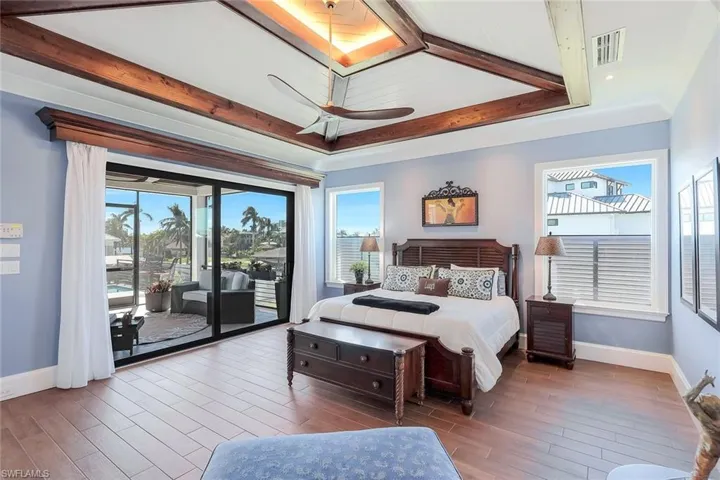 Bedroom with access to outside, hardwood / wood-style flooring, baseboards, beam ceiling, and a ceiling fan