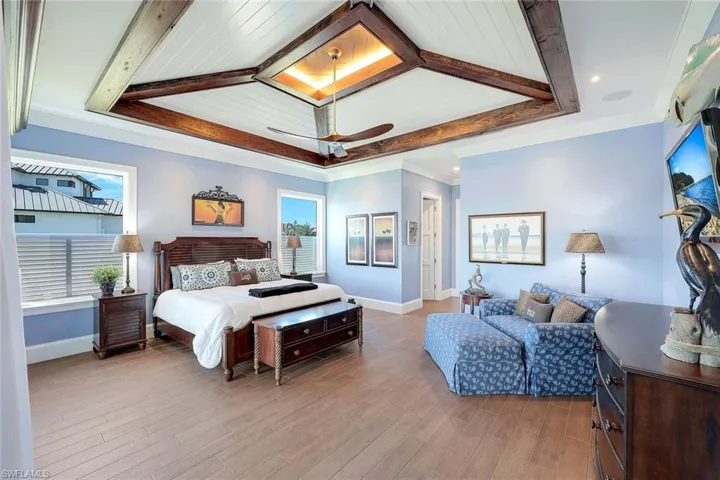 Bedroom featuring baseboards, multiple windows, wood finished floors, beam ceiling, and ceiling fan