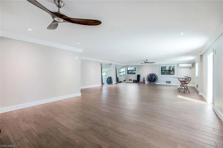 Workout area featuring a ceiling fan, wood finished floors, a wall mounted air conditioner, healthy amount of natural light, and recessed lighting