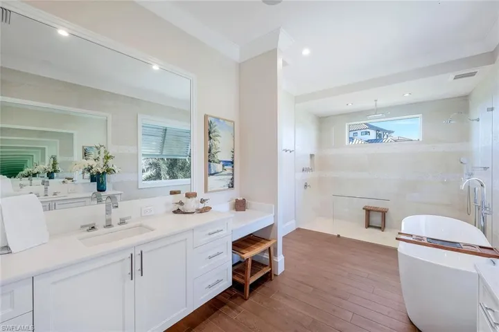 Full bath featuring a tile shower, hardwood / wood-style floors, vanity, a soaking tub, and recessed lighting