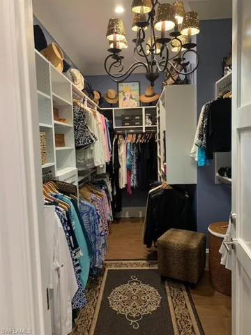 Spacious closet featuring a chandelier and wood finished floors