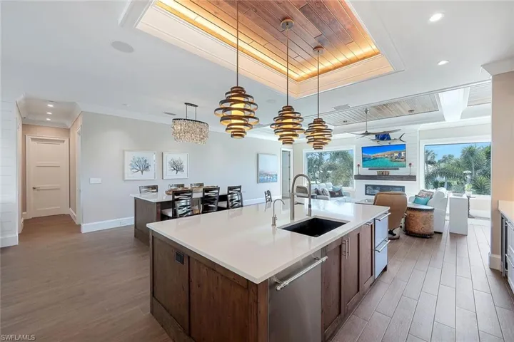 Kitchen featuring a sink, a kitchen island with sink, wood finished floors, recessed lighting, and ornamental molding