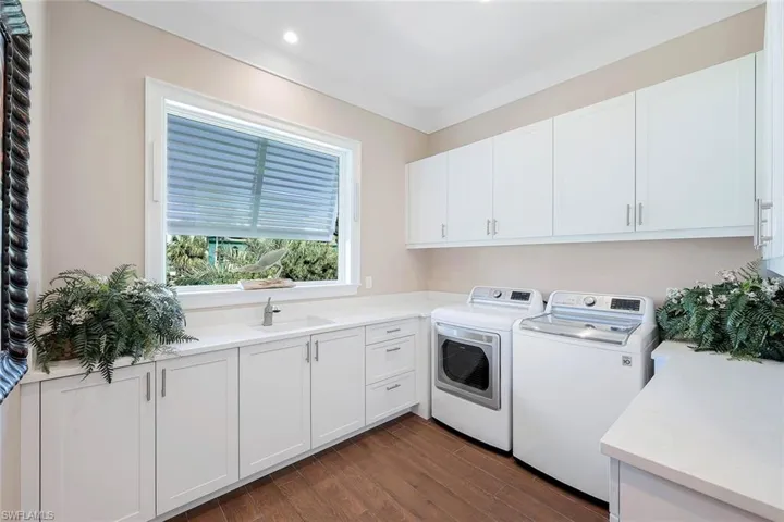 Clothes washing area featuring separate washer and dryer, cabinet space, recessed lighting, dark wood-style floors, and crown molding