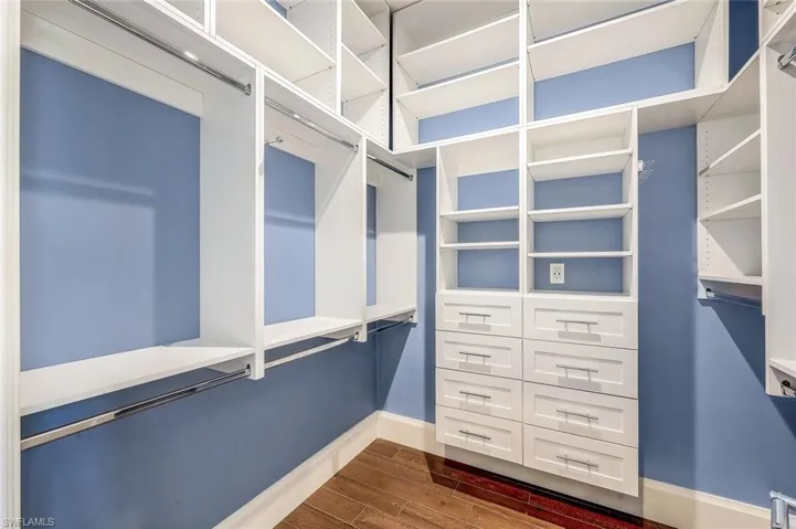 Walk in closet with dark wood-style flooring