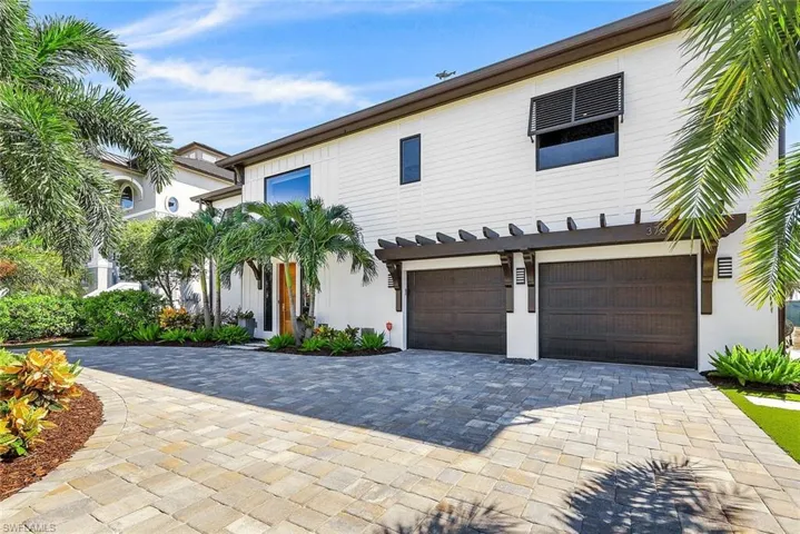 View of front facade with stucco siding, a garage, and decorative driveway