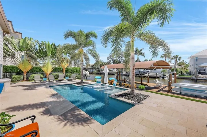 View of swimming pool with boat lift, a dock, a jacuzzi, a patio area, and a water view