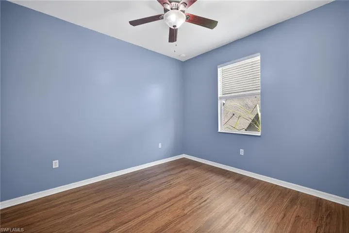 Spare room with dark wood-type flooring and a ceiling fan