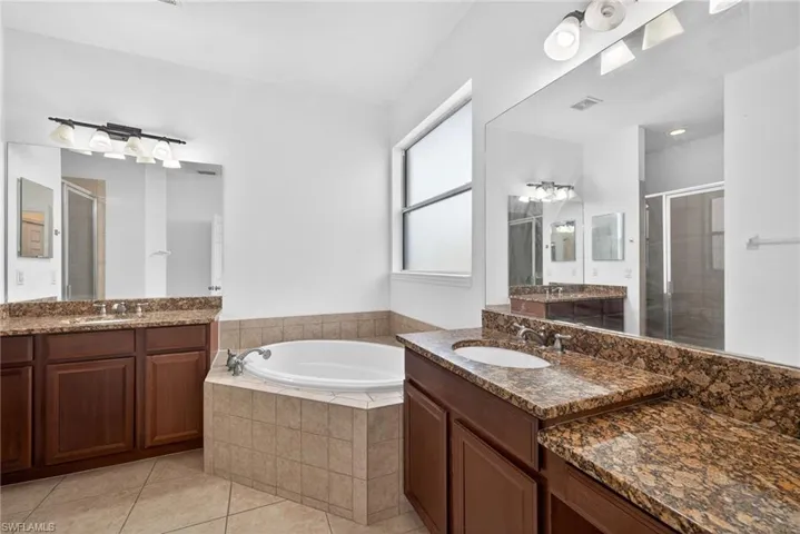 Bathroom with two vanities, a bath, and a shower stall