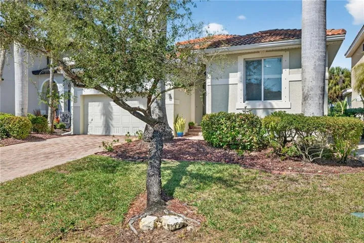 Mediterranean / spanish house featuring stucco siding, driveway, a garage, a front lawn, and a tile roof