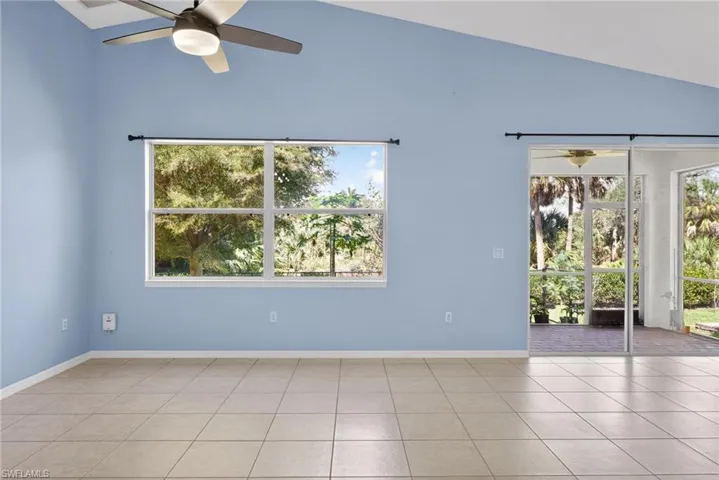 Spare room with a ceiling fan, vaulted ceiling, and light tile patterned floors