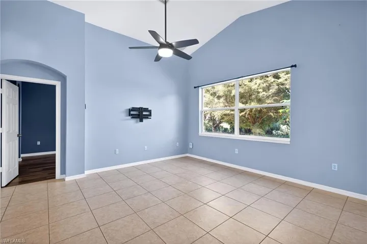 Unfurnished room featuring vaulted ceiling, a ceiling fan, and light tile patterned flooring