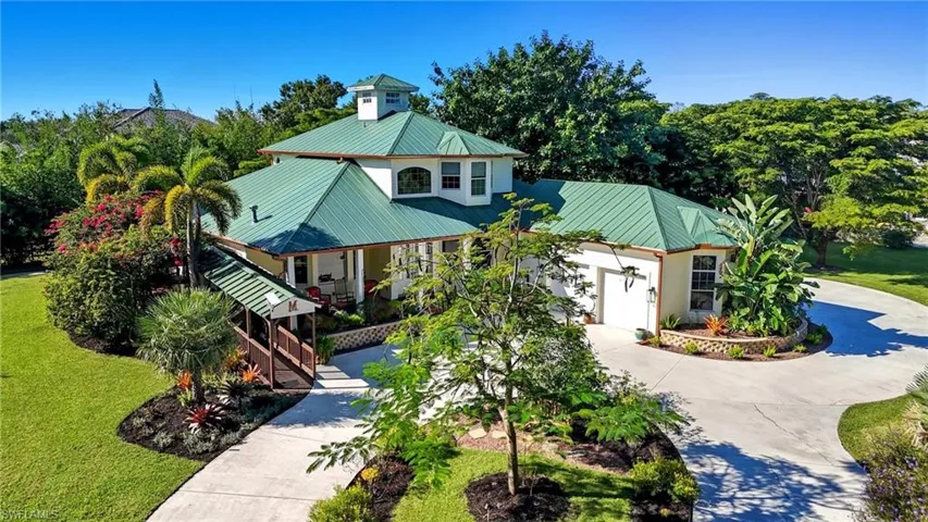 View of front facade with concrete driveway, a metal roof, a front yard, and covered porch