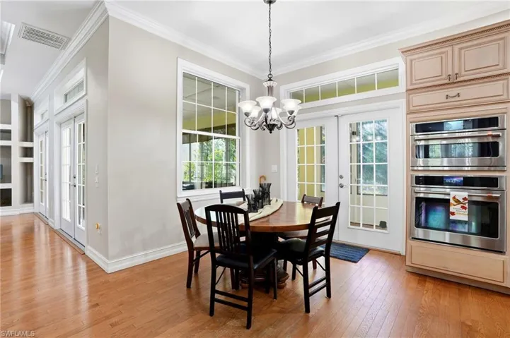 Dining space with french doors, crown molding, a chandelier, built in features, and light wood-style flooring