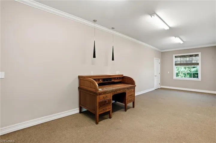 Carpeted office space featuring baseboards and ornamental molding