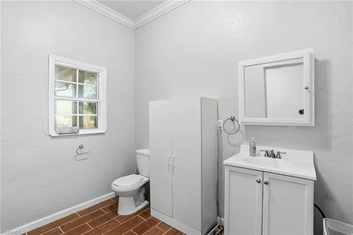 Half bathroom with a textured wall, wood tiled floors, crown molding, and vanity