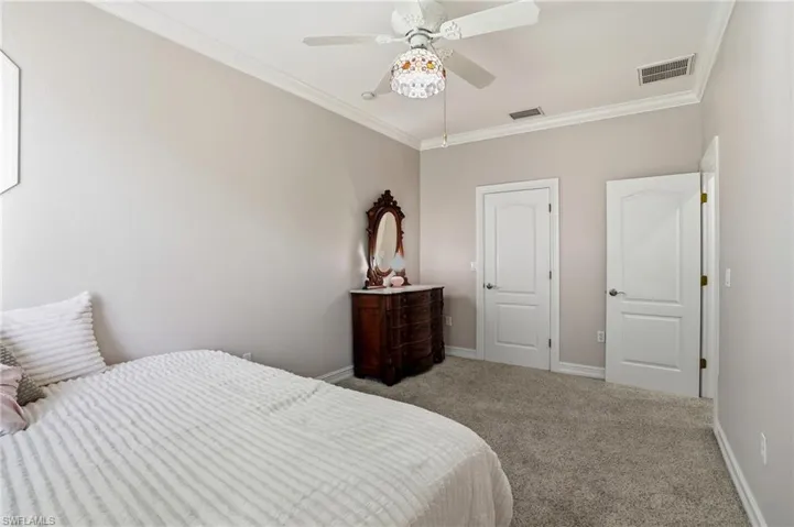 Carpeted bedroom with ornamental molding and ceiling fan