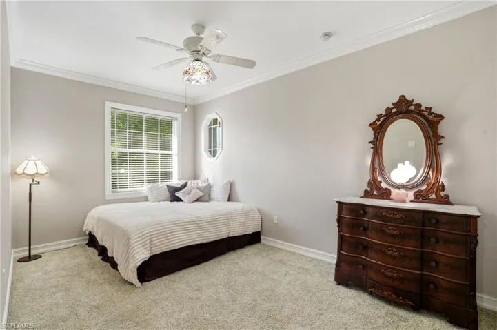 Bedroom with ornamental molding, light carpet, and a ceiling fan