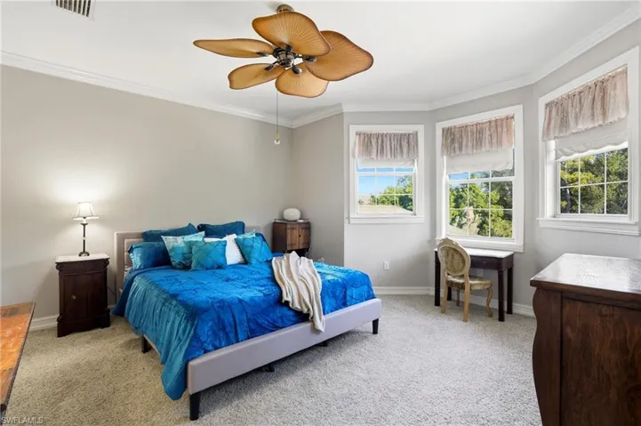 Bedroom featuring light colored carpet, ornamental molding, and ceiling fan