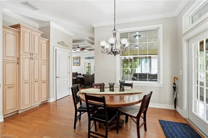 Dining space featuring light wood finished floors, plenty of natural light, a chandelier, crown molding, and ceiling fan