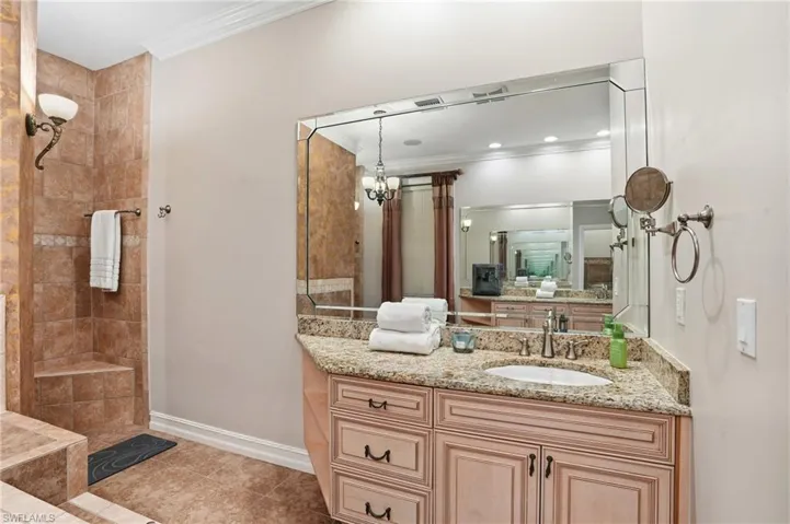 Full bathroom with crown molding, vanity, light tile patterned flooring, and a tile shower