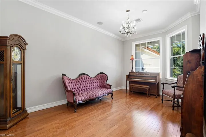 Living area featuring crown molding, hardwood / wood-style flooring, and a chandelier
