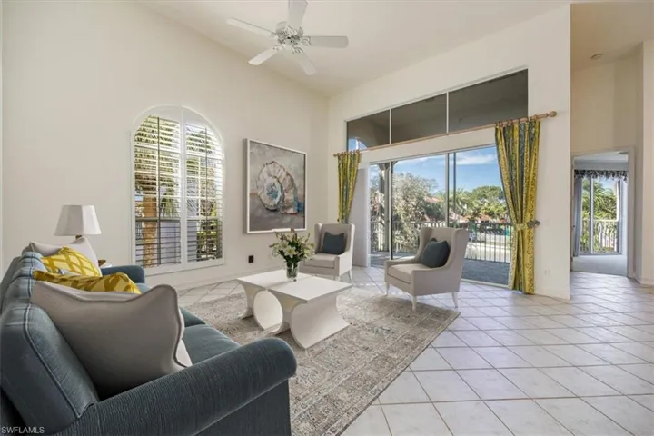 Living room featuring high vaulted ceiling, a ceiling fan, baseboards, and light tile patterned floors. Virtual Staging