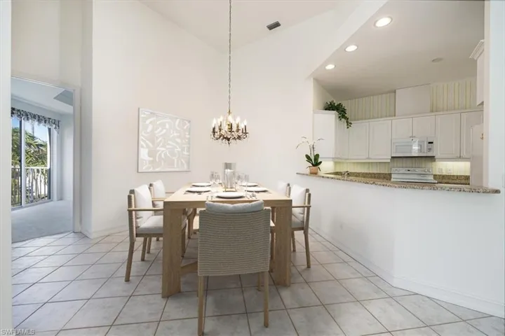Dining space featuring a notable chandelier, light tile patterned floors, , high vaulted ceiling, and baseboards /Virtual