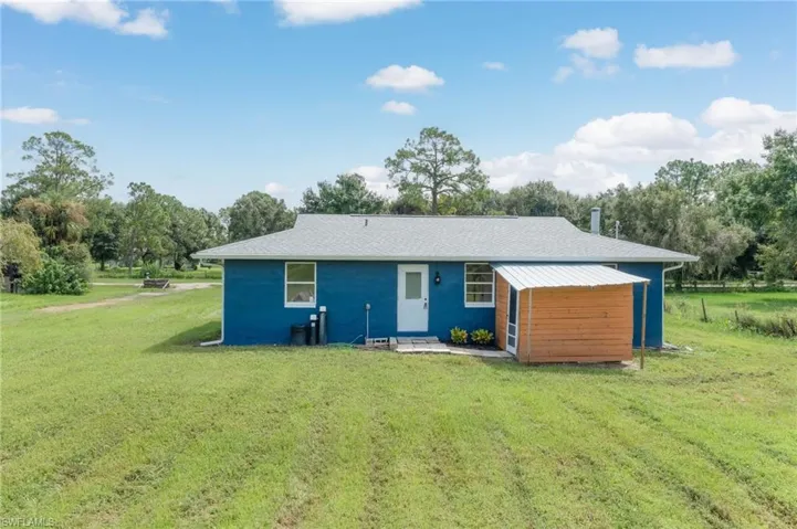 Rear view of property with a yard and a carport