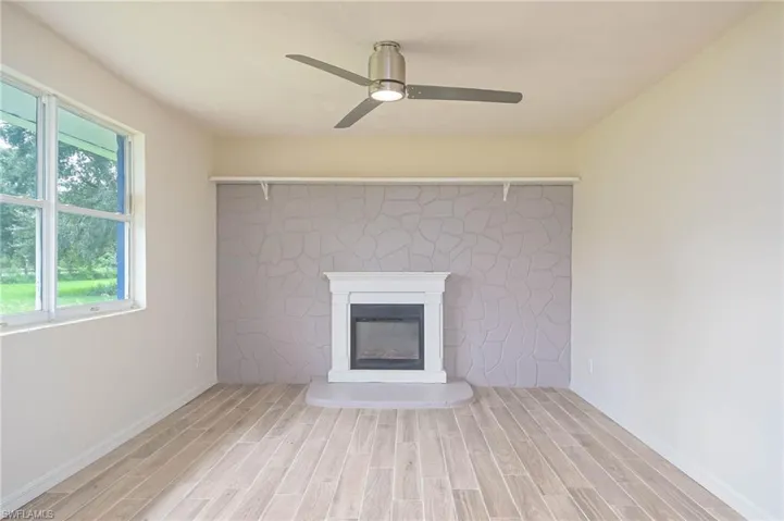 Unfurnished living room featuring a wealth of natural light, ceiling fan, and light hardwood / wood-style floors