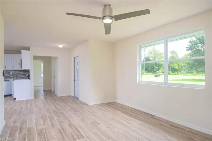 Unfurnished living room featuring ceiling fan, a wealth of natural light, and light hardwood / wood-style floors
