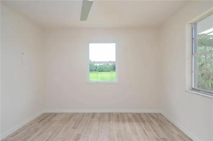 Spare room featuring a wealth of natural light, ceiling fan, and light wood-type flooring