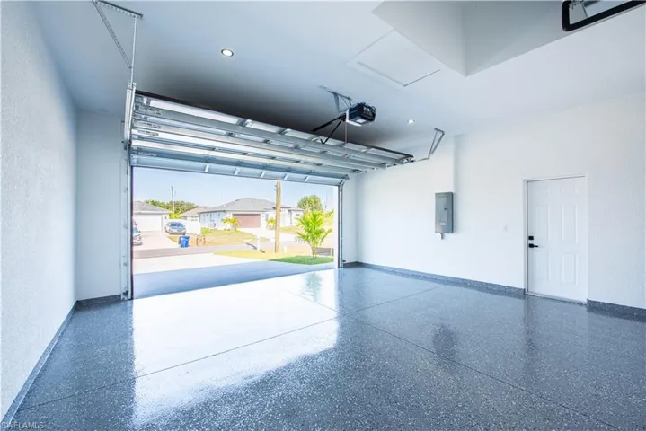 Garage featuring a textured wall, a residential view, electric panel, recessed lighting, and a garage door opener