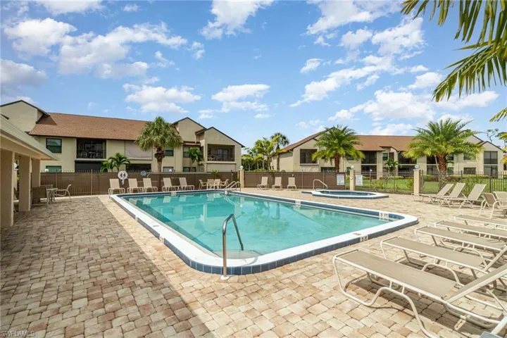 Community pool with a patio area, a hot tub, and a residential view