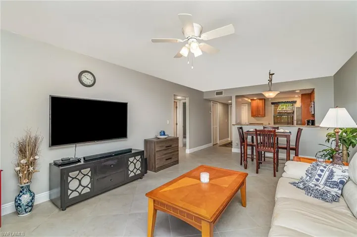 Living room with a ceiling fan and light tile patterned flooring