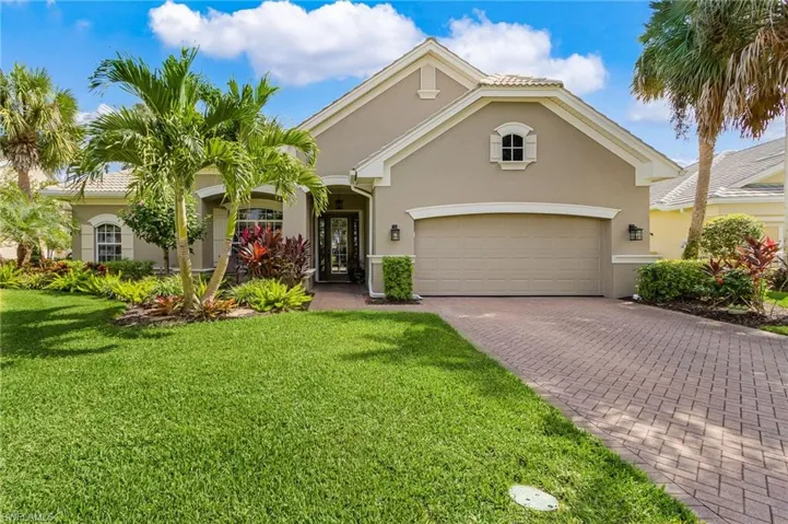View of front facade with large yard and long driveway in pavers
