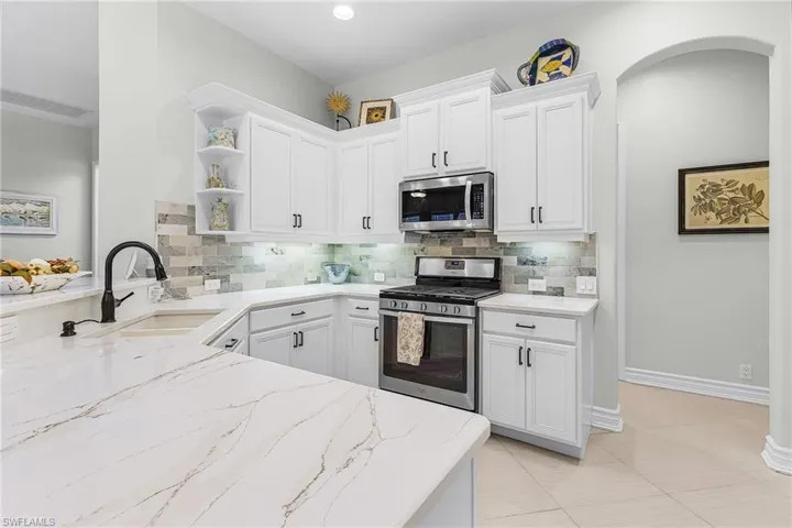 Updated kitchen with white cabinets, quartz counters and beautiful backsplash