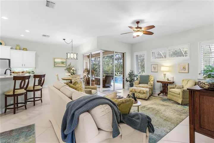 Living room with light walls, tiled floor, ceiling fan off pool area